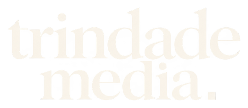 Nome trindade media em duas linhas serifadas, em branco perolado, com ponto quadrado.